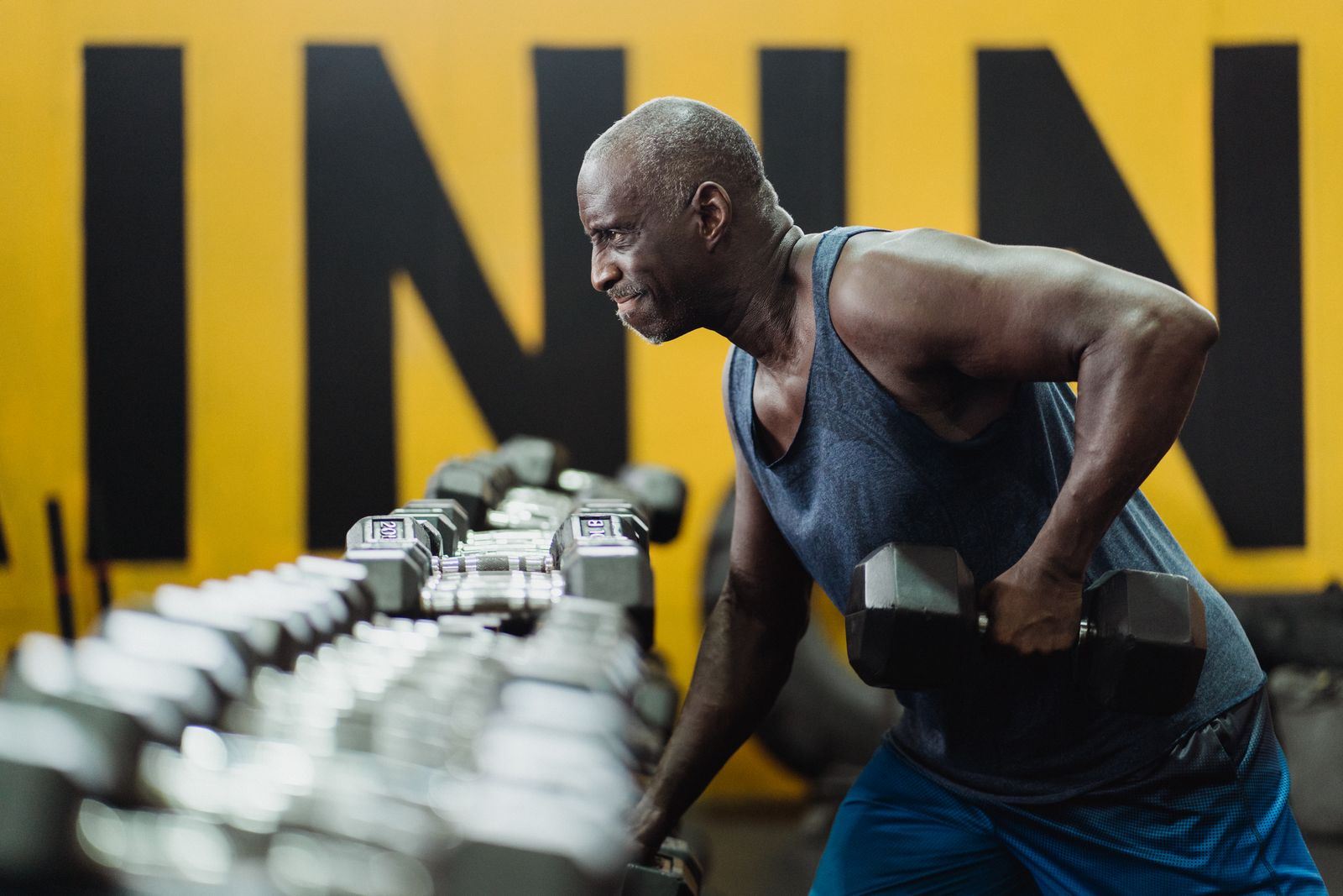 Man op leeftijd traint met dumbbells in een sportschool