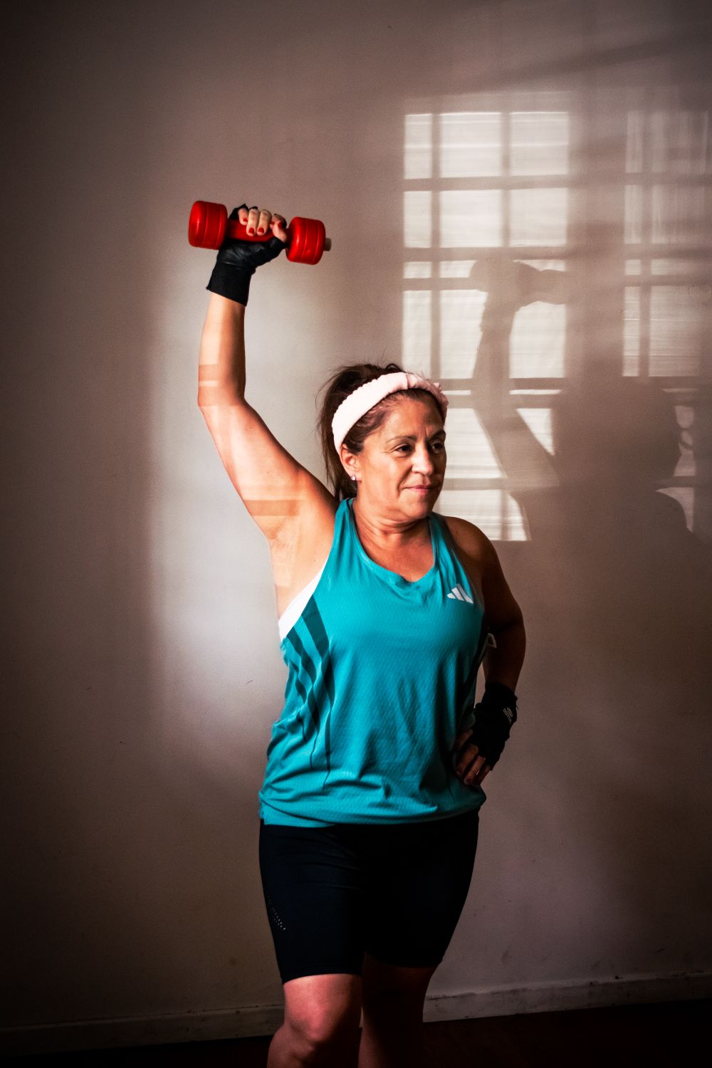Vrouw van middelbare leeftijd drukt een dumbbell boven haar hoofd
