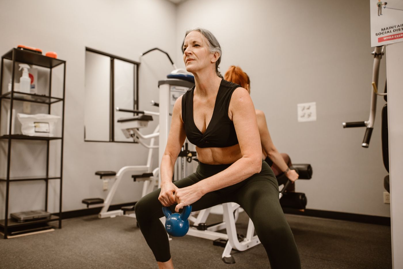 Vrouw van rond de zestig doet een squat met een kettlebell