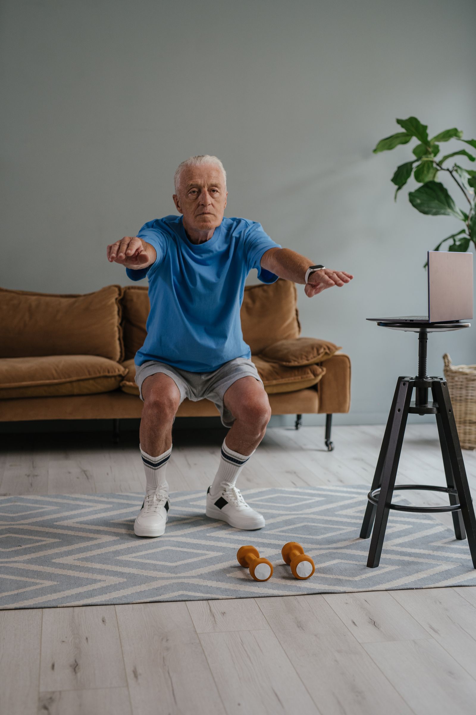 Oudere man doet een kniebuiging in zijn eigen woonkamer